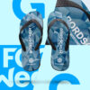 Ein Paar Flip-Flops auf einem hellblauen Hintergrund. Die Sohlen haben ein abstraktes, geometrisches Muster in verschiedenen Blautönen. Die schwarzen Riemen sind mit der Aufschrift „BORDSCHUH #WIRSINDMARINE“ und dem Logo der Bundeswehr bedruckt. Ein vergrößerter Ausschnitt des Musters und der Aufschrift ist im oberen rechten Bereich des Bildes zu sehen.