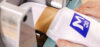 Ein Mitarbeiter schiebt einen weißen Gegenstand mit dem blauen Logo "gc M" in eine graue Maschine.