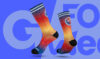 Ein Paar Socken mit einem Farbverlauf von Rot zu Blau, auf denen das Logo "#WRMNGHS" zu sehen ist, vor einem blauen Hintergrund mit dem weißen Schriftzug "GOOD WEEK".