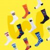Eine Auswahl an Socken von verschiedenen Marken wie "Tchibo", "Miba" und "Mr. Red" sind vor einem gelben Hintergrund ausgestellt.