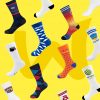 Eine Auswahl an Socken von verschiedenen Marken wie "Tchibo", "Miba" und "Mr. Red" sind vor einem gelben Hintergrund ausgestellt.