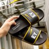 Verschiedene Badelatschen und Badeschuhe sind auf einem gelben Hintergrund mit dem Logo "GC FOOTwear" ausgestellt. Zu sehen sind unter anderem Badelatschen von Hela, Knott, Bayer Leverkusen, NFT und West.