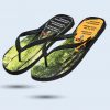 Ein schwarzer Flip-Flop mit einem Motiv von einem Wald mit hohen Bäumen, der sich in einem gelben Feld befindet. Auf der Sohle sind das Logo von "GC FOOTwear" und die Schriftzüge "ECO-TEX INK" und "ECO-ENERGY" zu sehen.
