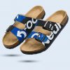 Ein Paar Badesandalen mit Korkfußbett und schwarzen, blauen und weißen Riemen. Die Riemen sind mit Buchstaben bedruckt im branding von GC Footwear.