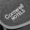 Eine Detailaufnahme grauer Slipper mit verstellbarem Riemen, auf dem der Schriftzug "Comwell HOTELS" zu sehen ist.
