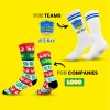 Two pairs of customisable socks on a yellow background. At the top, a white pair with blue stripes and a club logo, as well as the inscription “#12 Max” and the text “For clubs”. At the bottom, a colourful pair in red, green and white with a Christmas pattern, snowflakes and reindeer, as well as the text “For companies” and a placeholder logo.