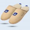 A beige slipper with a white, fluffy lining. The “GC FOOTWEAR” logo and the phrase “Step up your brand” are featured on the side.