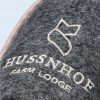 Detailed close-up of the gray felt texture of a slipper, showing the high-quality embroidery of the logo and the name “HUSSNHOF FARM LODGE” in cream-colored thread.