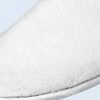 A detailed picture of a pair of white hotel slippers with plush material.