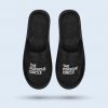 A top-down view of a pair of black house slippers arranged vertically. The footwear features a cushioned sole and the official “THE PORSCHE CIRCLE” design centered on the instep.