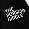 A macro close-up showing the soft texture of the black material and the crisp white print of the text “THE PORSCHE CIRCLE,” highlighting a small purple graphic detail at the end.